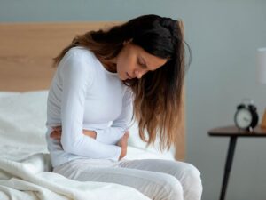Mujer con colon irritable en la cama sentada y planteándose consumir probóticos